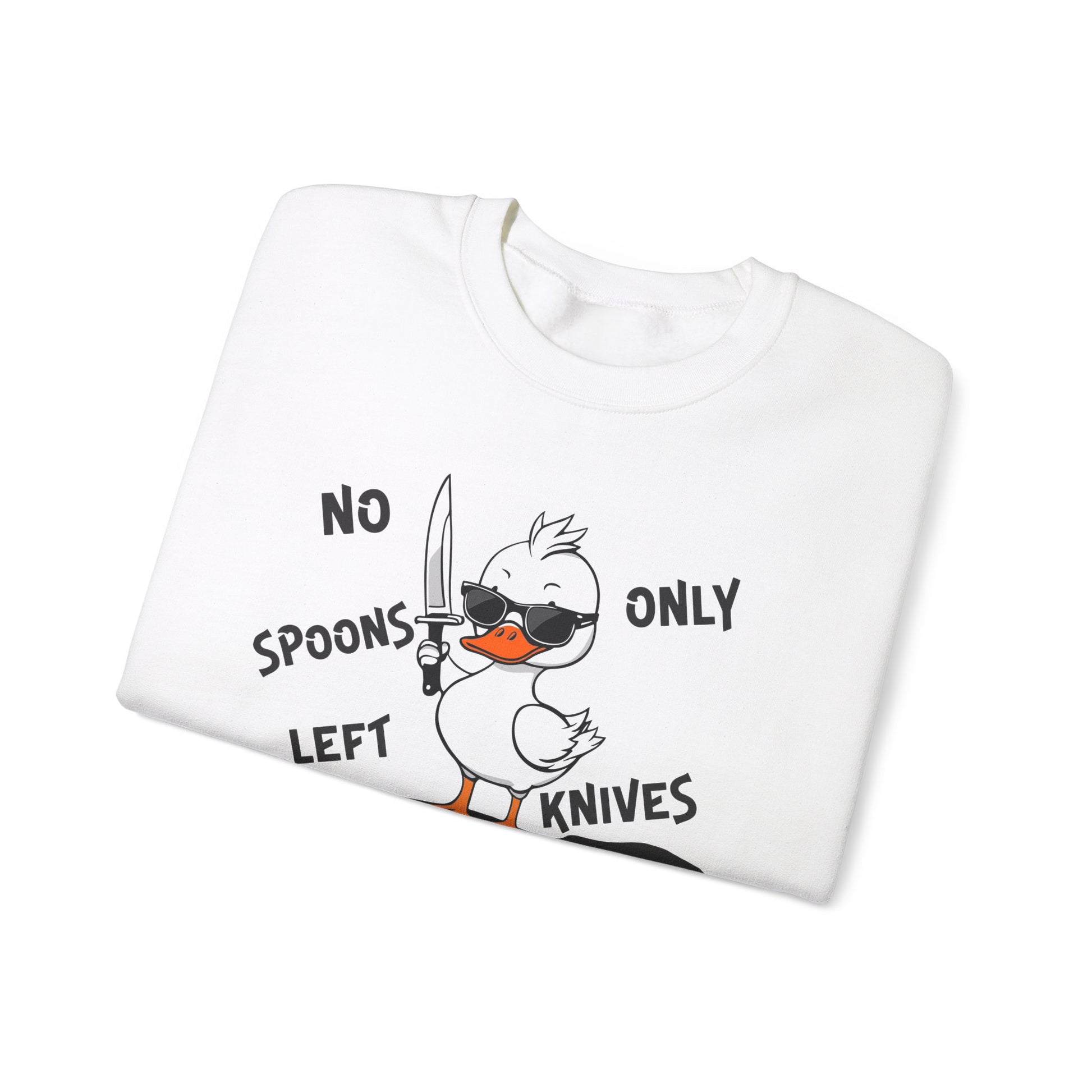 This image shows a white crewneck sweatshirt folded neatly. The sweatshirt features a cartoon design of a duck holding a knife, standing in a puddle of spoons. The text around the duck reads “NO SPOONS LEFT, ONLY KNIVES.” The sweatshirt is displayed against a plain white background, clearly showcasing the design and text.