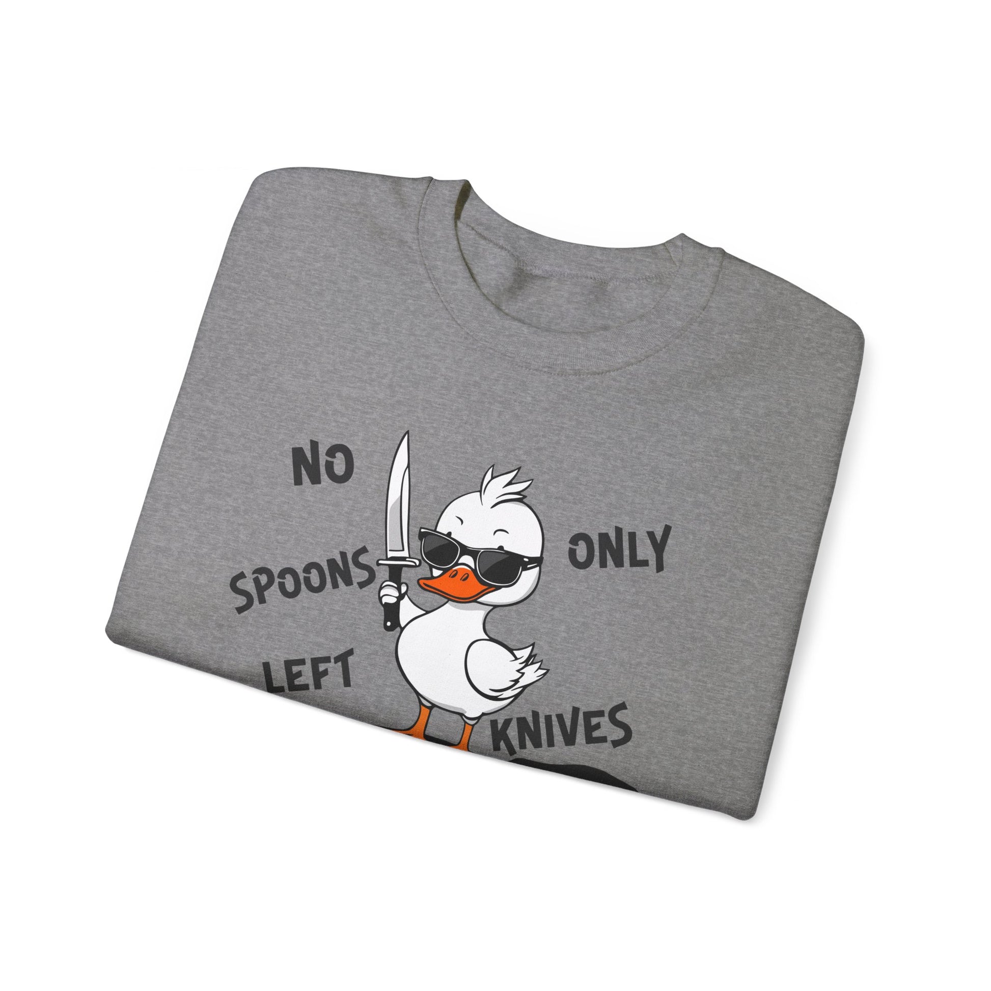 This image shows a graphite heather-colored crewneck sweatshirt folded neatly. The sweatshirt features a cartoon design of a duck holding a knife, standing in a puddle of spoons. The text around the duck reads “NO SPOONS LEFT, ONLY KNIVES.” The sweatshirt is displayed against a plain white background, clearly showcasing the design and text.