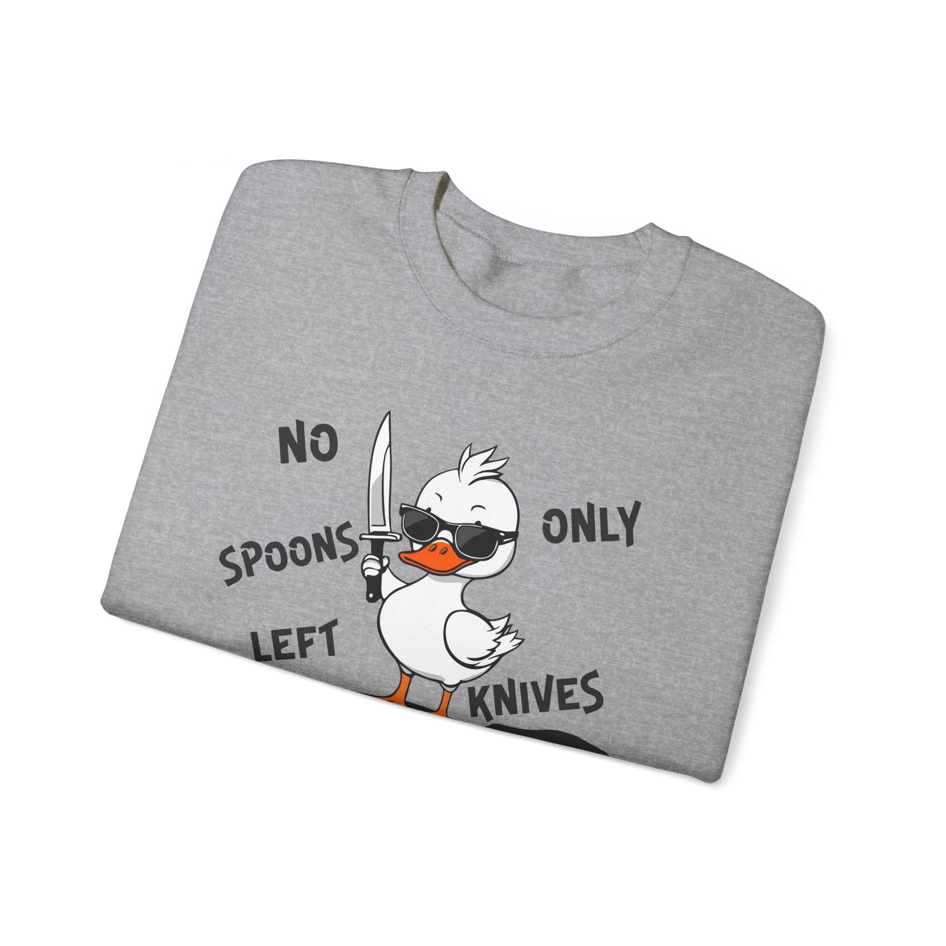 This image shows a sport grey-colored crewneck sweatshirt folded neatly. The sweatshirt features a cartoon design of a duck holding a knife, standing in a puddle of spoons. The text around the duck reads “NO SPOONS LEFT, ONLY KNIVES.” The sweatshirt is displayed against a plain white background, clearly showcasing the design and text.