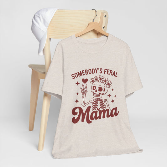 Heather Dust tee printed with a flower-crowned skeleton giving a peace sign, reading "SOMEBODY'S FERAL MAMA".
