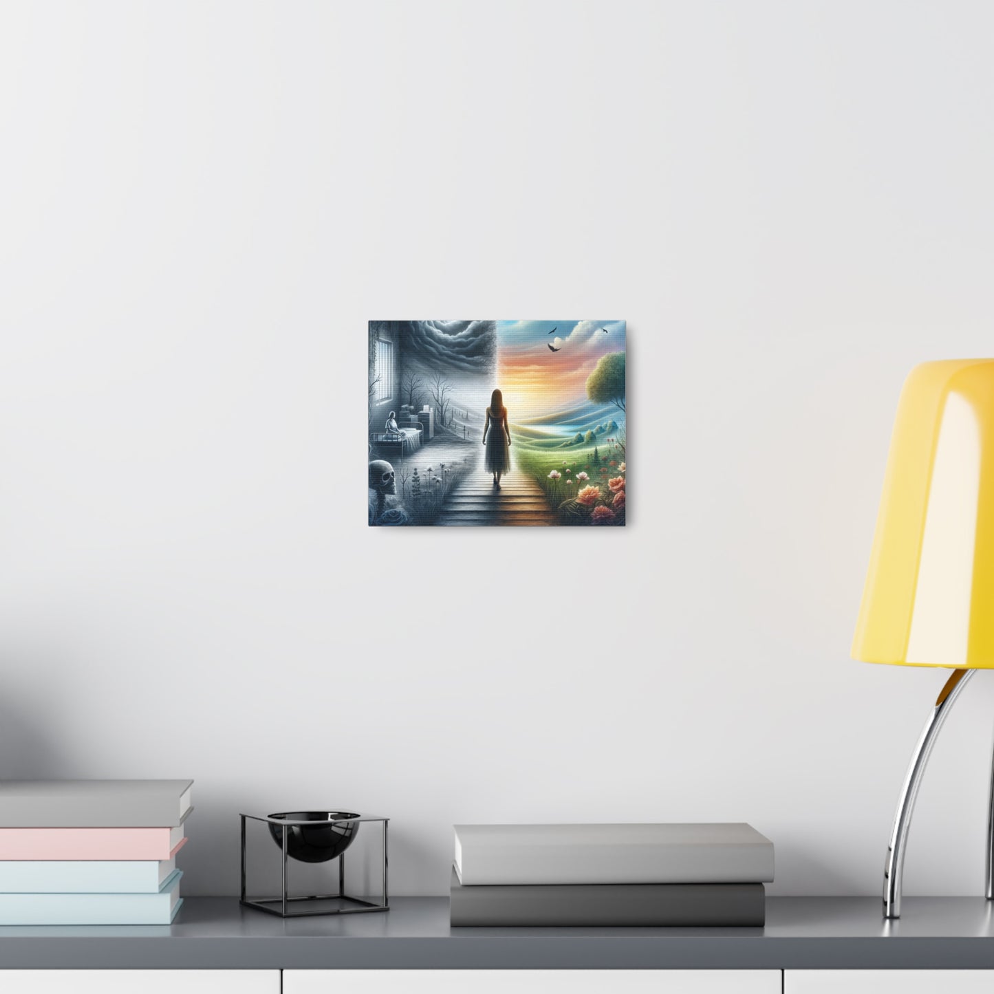 A canvas gallery wrap titled “Thru Darkness: a Journey of Resilience” hangs on a white wall above a modern shelf. The shelf holds stacked books, a small black bowl, and is next to a yellow lamp. The artwork depicts a powerful contrast between dark and light, symbolizing a journey from despair to hope.