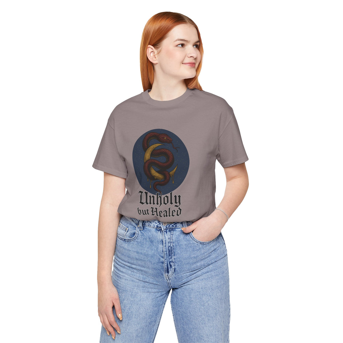 Pebble Brown tee printed with a maroon snake coiled around a gold crescent moon, reading "Unholy but Healed".