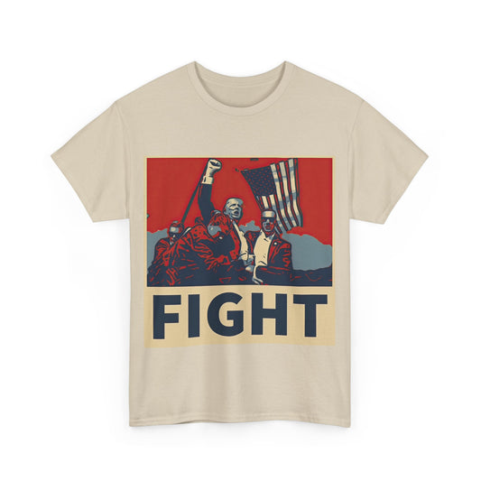 This image shows a sand colored unisex heavy cotton t-shirt with a graphic design on the front. The design features a stylized, poster-like illustration of former President Donald Trump, raising his fist and standing in front of an American flag. The word “FIGHT” is prominently displayed at the bottom of the illustration in bold capital letters. The graphic uses a color palette reminiscent of red, white, and blue, contributing to a patriotic theme. The t-shirt is displayed on a plain white background.