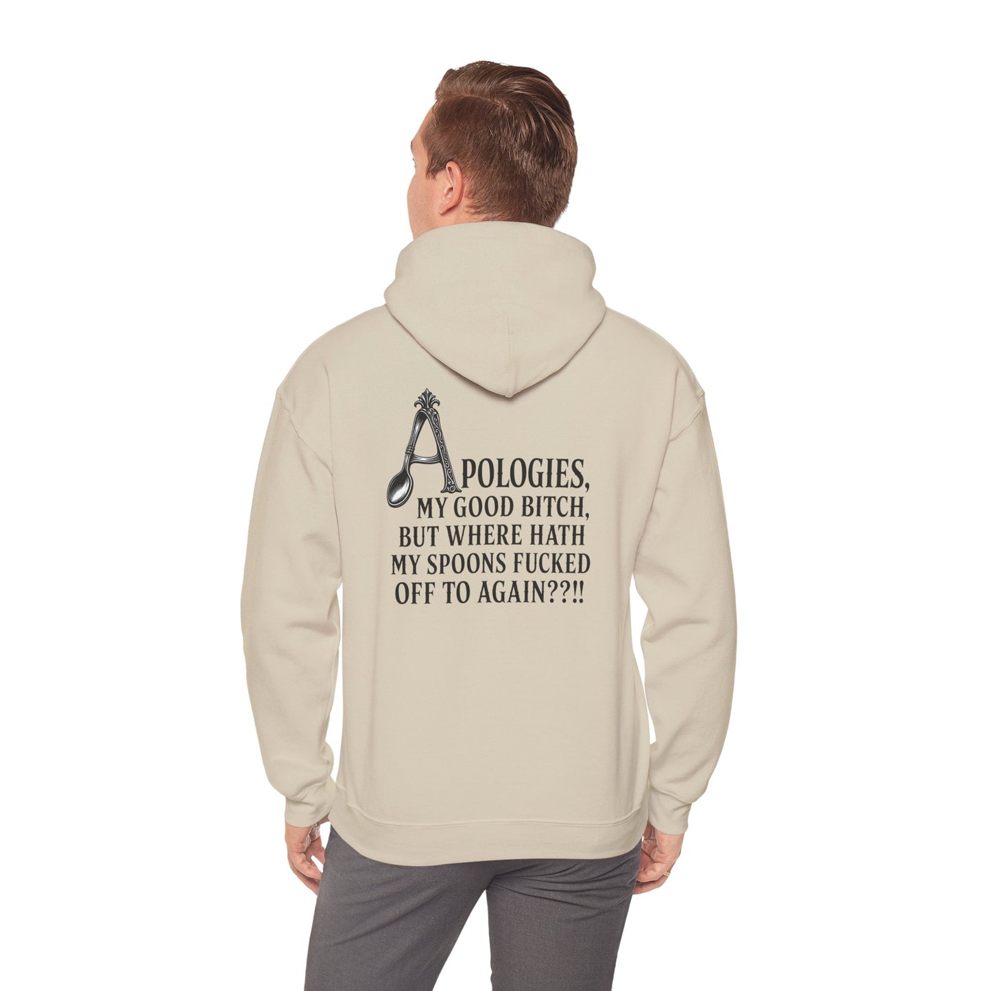 A man viewed from behind wearing a beige pullover hoodie with a black graphic and text on the back, paired with gray pants.