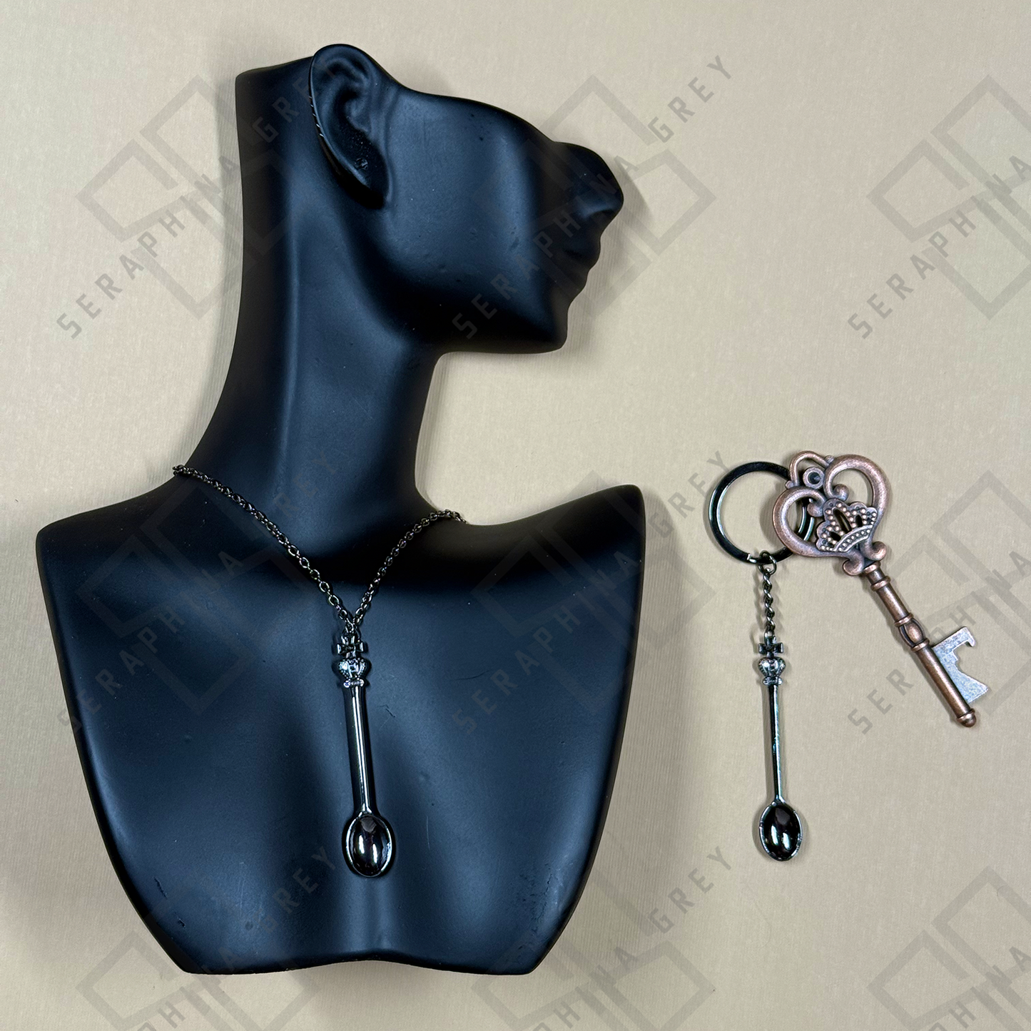 Black Spoon-shaped necklace and keychain on a black mannequin bust with a branded background.
