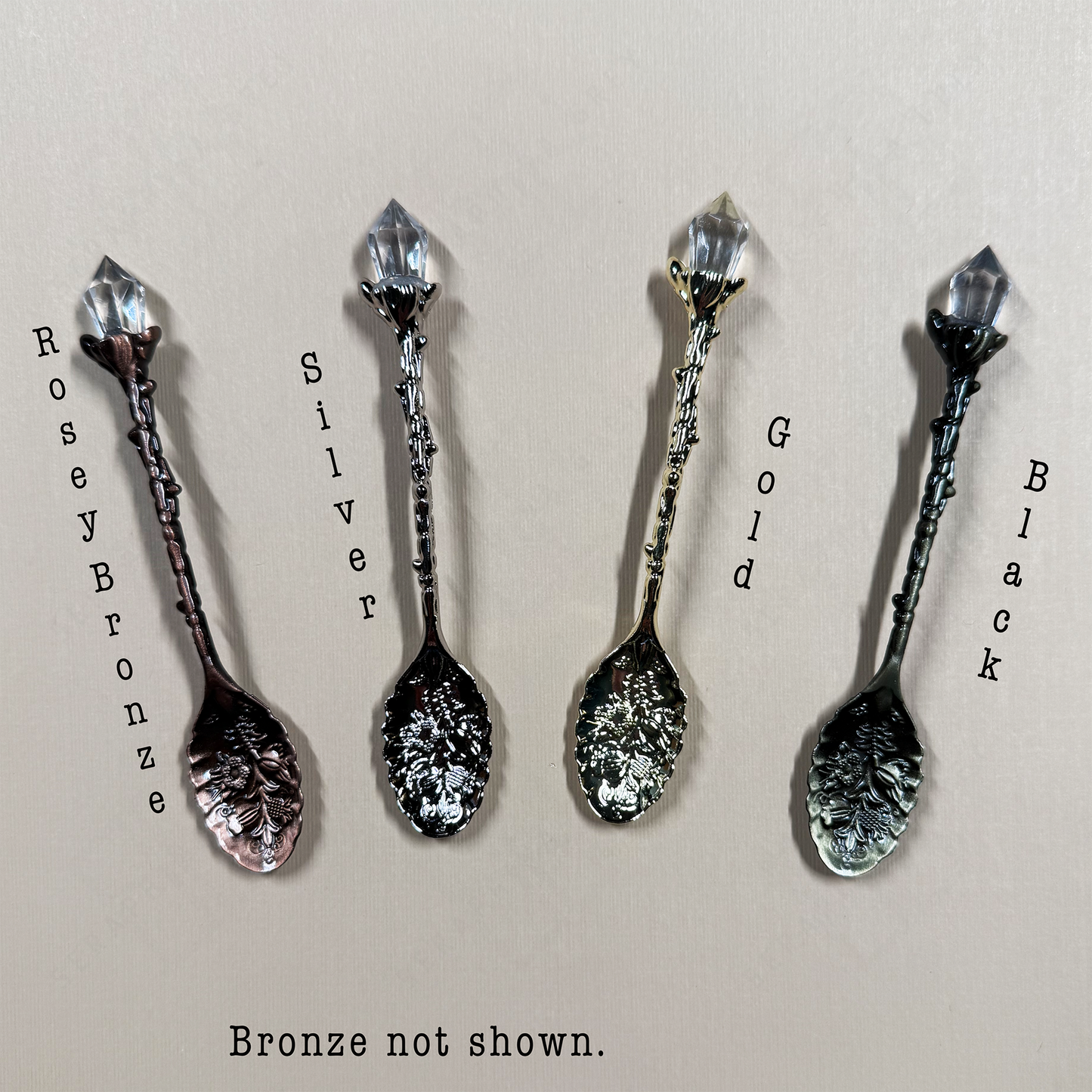 Four decorative spoons in different finishes on a beige background