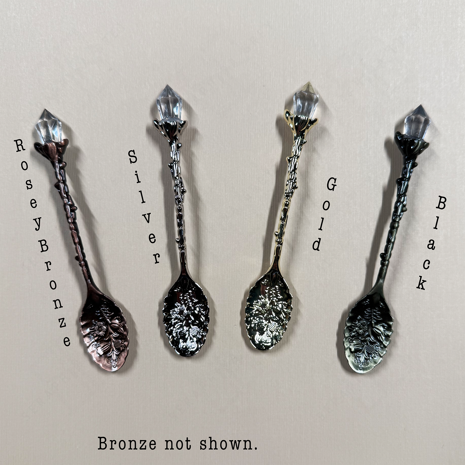 Four decorative spoons in different finishes on a beige background