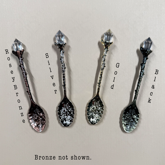 Four decorative spoons in different finishes on a beige background