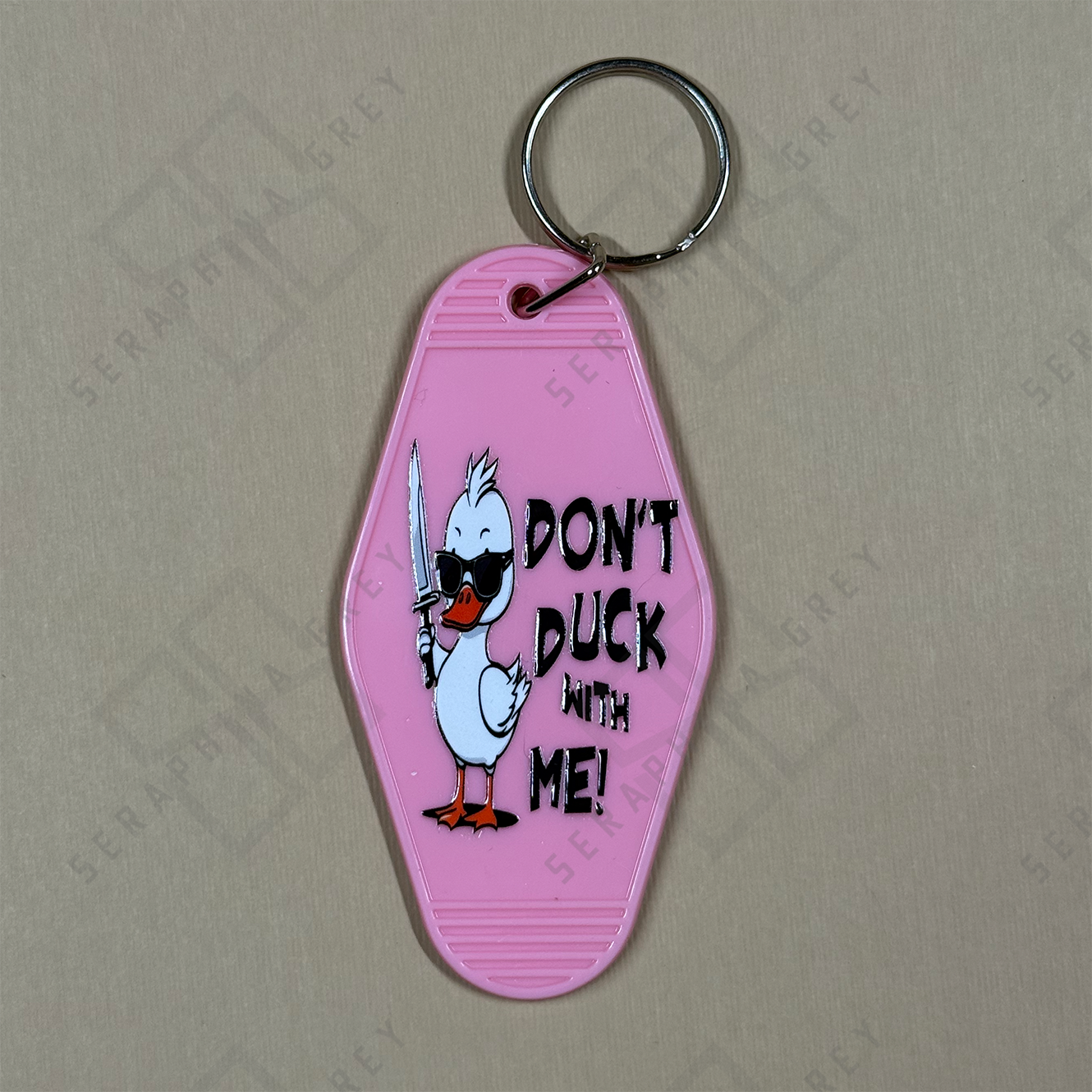 Pink keychain with cartoon duck and text 'Don't Duck with Me' on a beige background