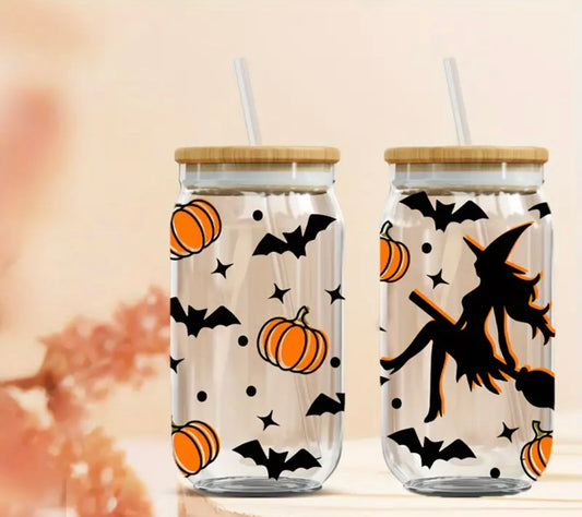 16 oz glass tumbler with a bamboo lid and reusable straw, featuring a Halloween design with black bats, orange pumpkins, and a silhouette of a witch riding a broomstick. The tumbler is perfect for spooky season sips.