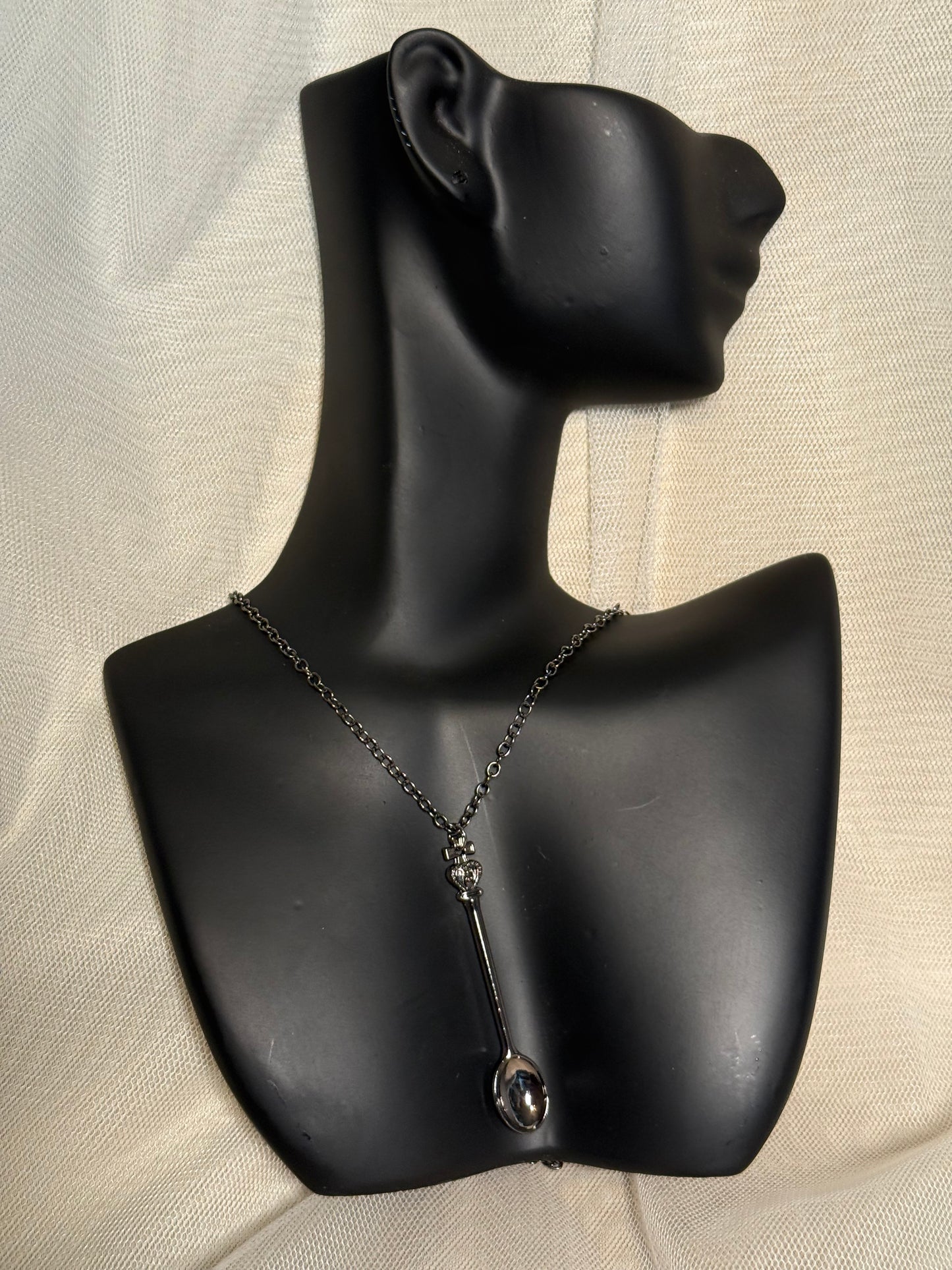 Spoon-shaped pendant necklace on a black jewelry bust