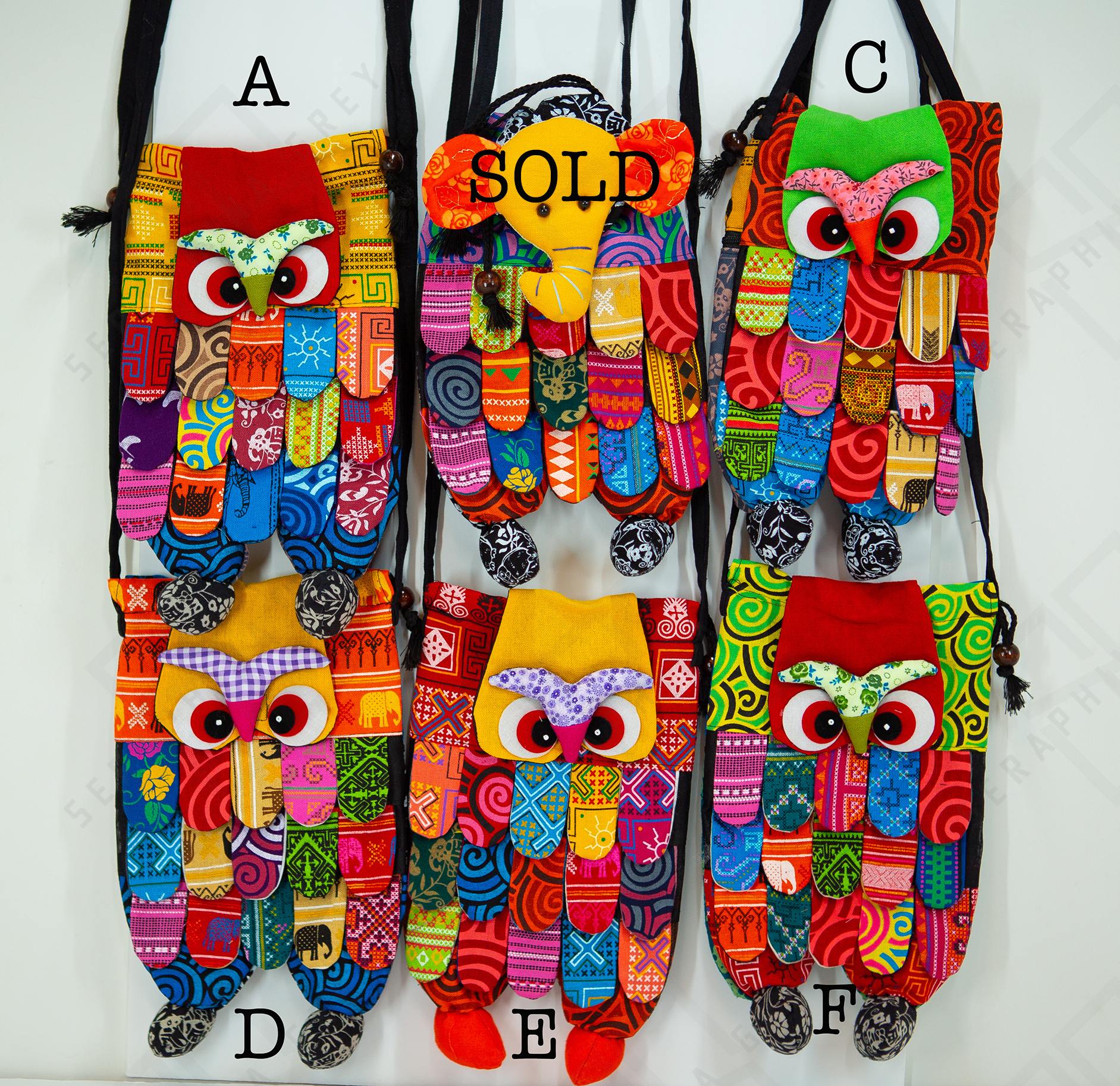 This image features a collection of handmade owl handbags displayed on a white background. Each handbag is uniquely designed with colorful, patchwork patterns and intricate details. The bags are arranged in two columns, labeled A, C, D, E, and F. One of the bags is marked as “SOLD.” The owl handbags have distinctive eyes and beaks, with the body made up of various patterned fabrics, creating a vibrant and eclectic look. The handbags hang by black straps, showing their design and structure clearly.