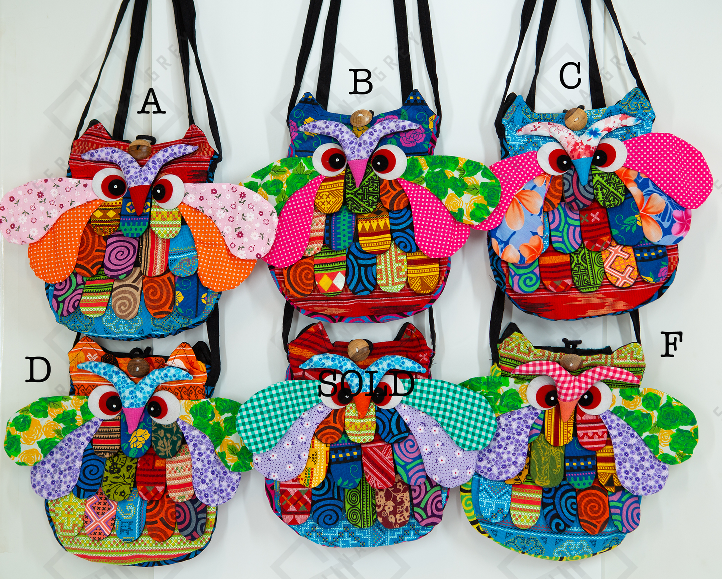 The image shows six colorful owl-shaped bags labeled A, B, C, D, and F. Each bag features a unique combination of vibrant patterns and colors, including floral, geometric, and abstract designs. The bags have large, expressive eyes and detailed wings, adding a playful and whimsical touch. Bag D is marked as “SOLD.” The bags are displayed against a white background and hung by their straps.