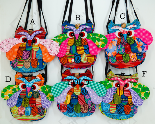 The image shows six colorful owl-shaped bags labeled A, B, C, D, and F. Each bag features a unique combination of vibrant patterns and colors, including floral, geometric, and abstract designs. The bags have large, expressive eyes and detailed wings, adding a playful and whimsical touch. Bag D is marked as “SOLD.” The bags are displayed against a white background and hung by their straps.