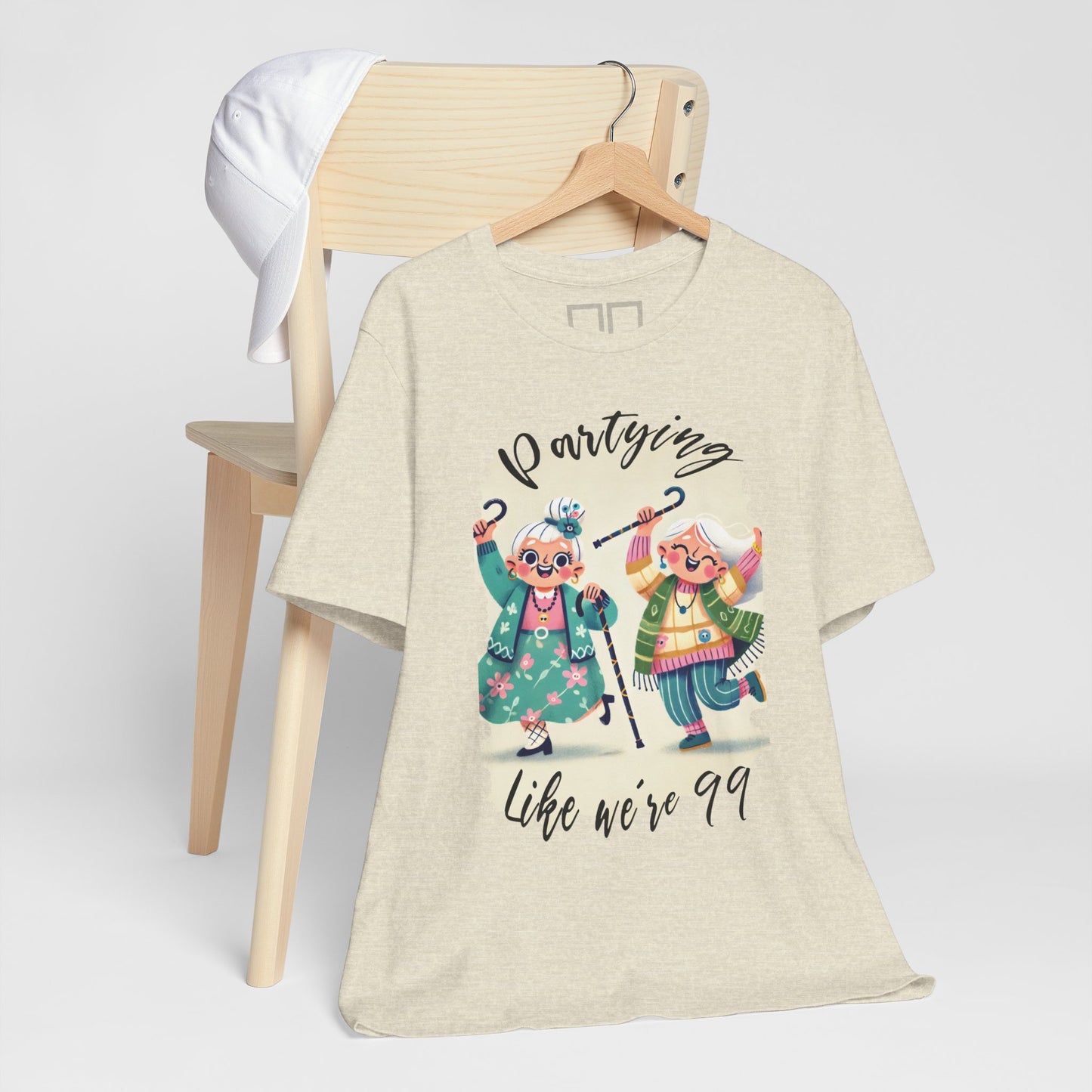 A beige unisex jersey t-shirt with a graphic print of two dancing cartoon characters and the text 'Partying like we're 99'.