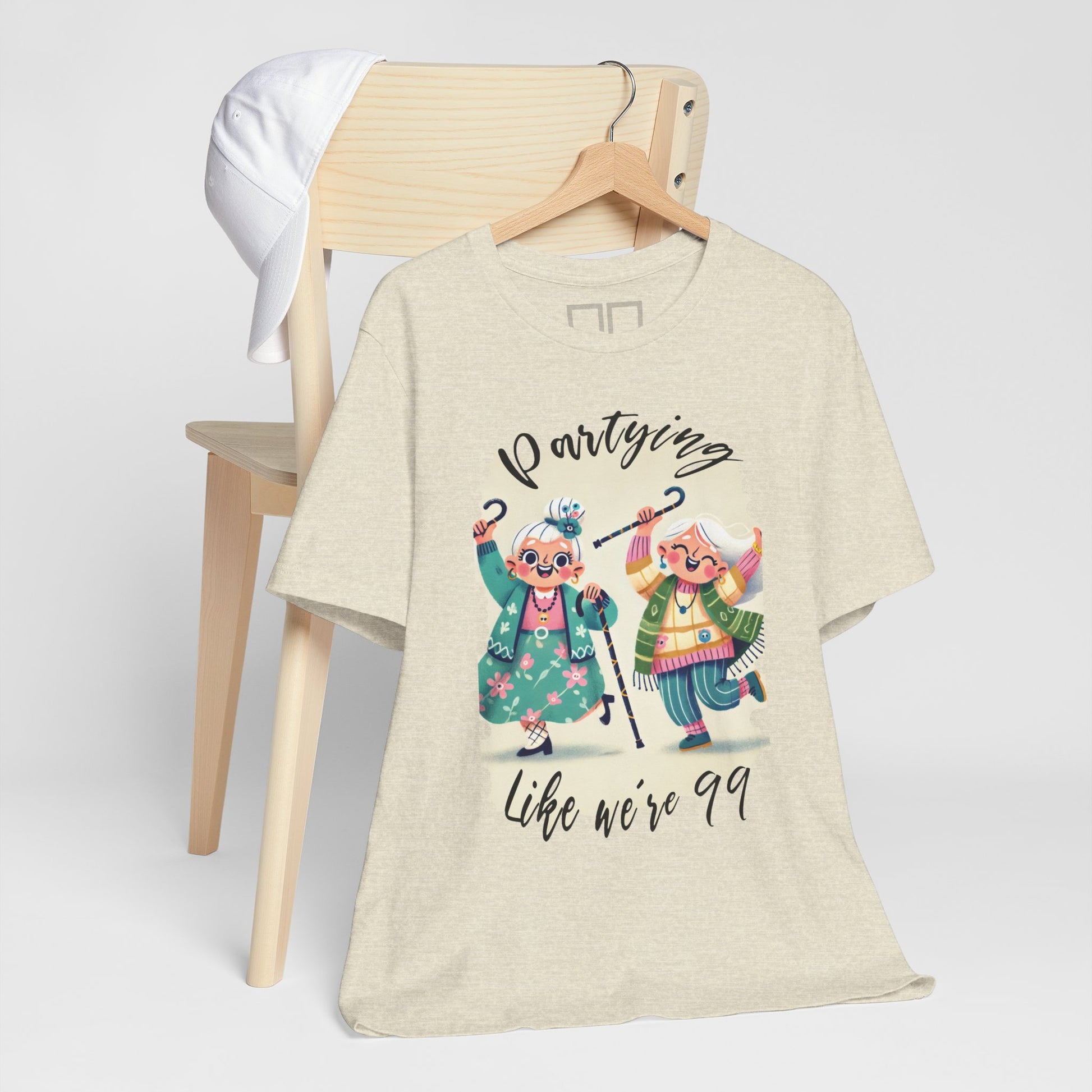 A beige unisex jersey t-shirt with a graphic print of two dancing cartoon characters and the text 'Partying like we're 99'.