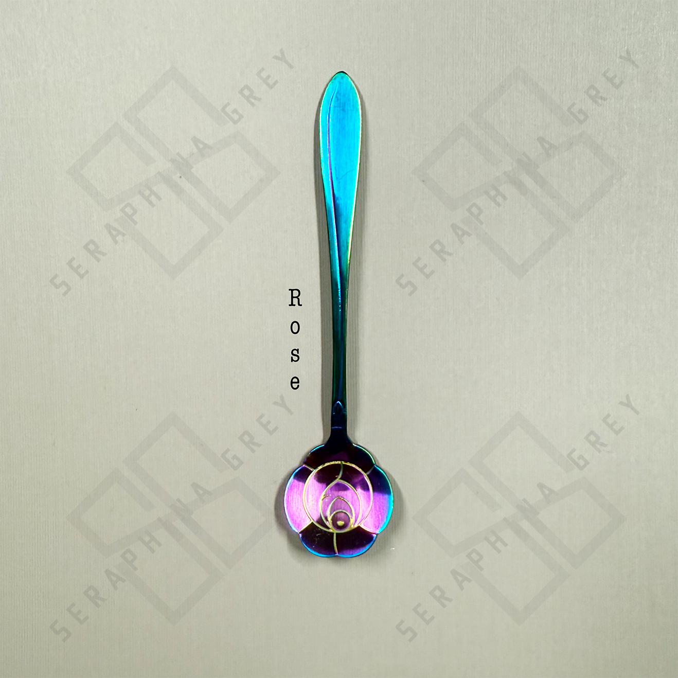 Rainbow colored Rose spoon against a light gray background 