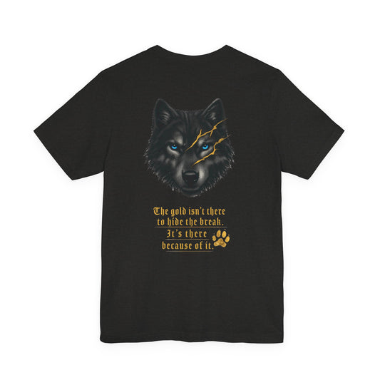 Black Heather unisex T-shirt shown from the back, featuring a wolf with bright blue eyes and gold kintsugi-style scars above the text, “The gold isn’t there to hide the break. It’s there because of it,” with a gold paw print below.