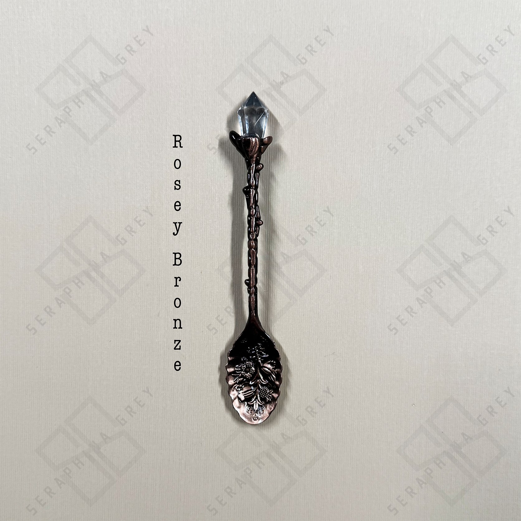 Rosey Bronze colored crystal tipped spoon on cream background
