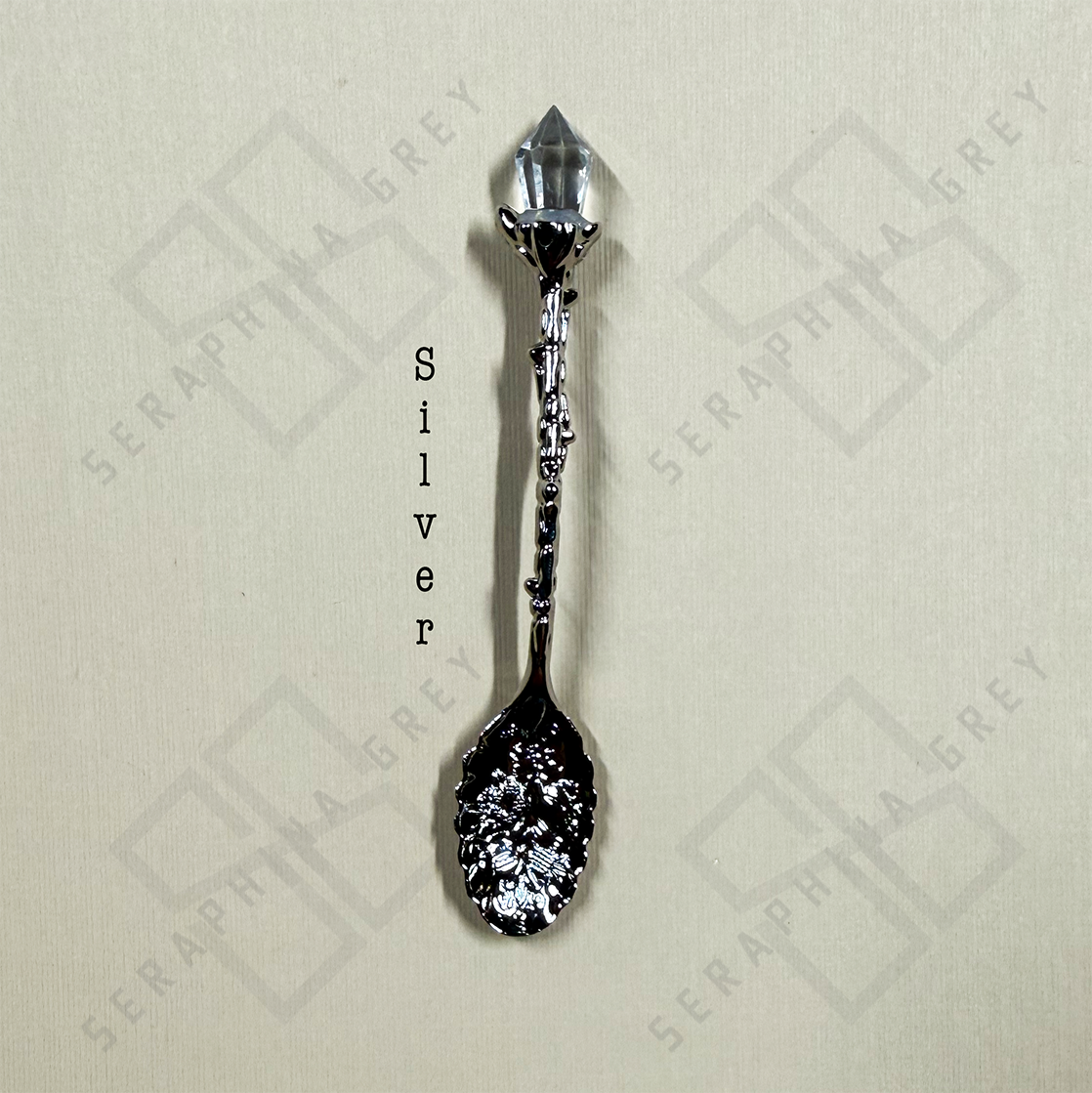 Silver colored crystal tipped spoon on cream background