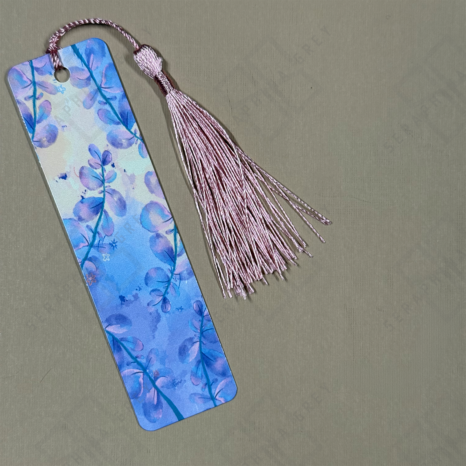 Bookmark with floral design and pink tassel on a beige background