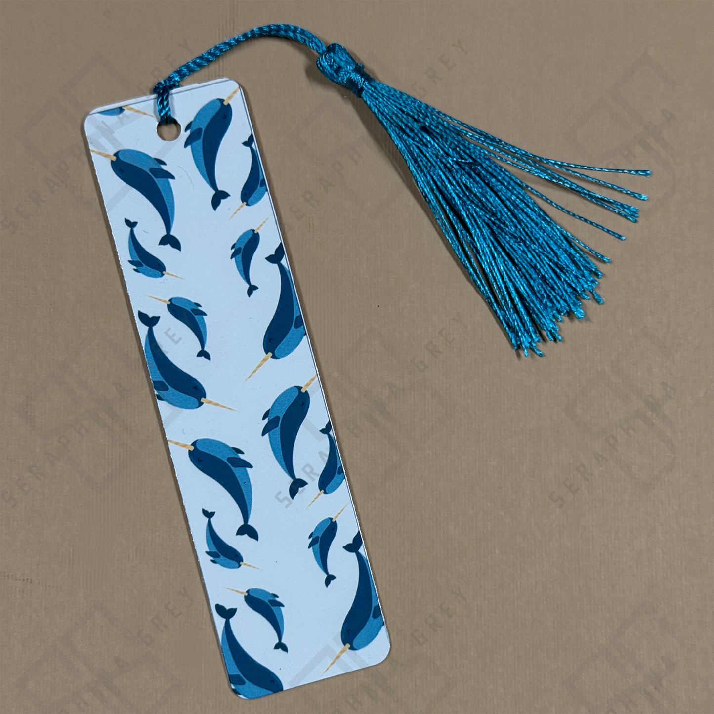 Bookmark with Norwhal pattern and blue tassel on a beige background