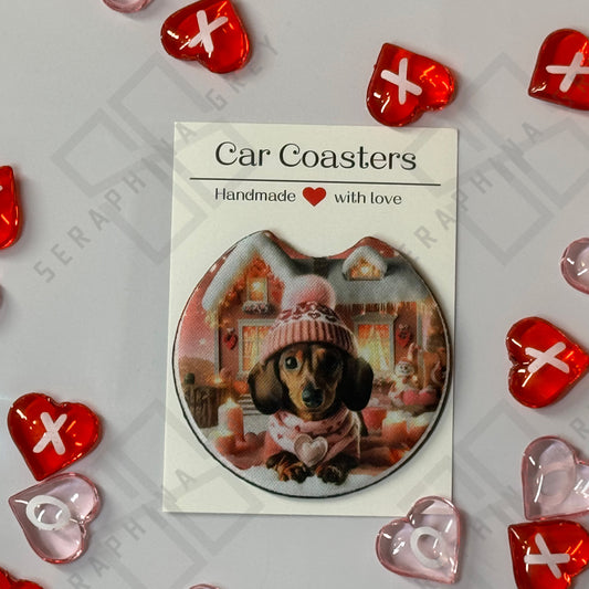 A single car coaster with a design of a dachshund dog wearing a pink hat and scarf, set against a cozy holiday backdrop. The coaster is packaged with a label that reads ‘Car Coasters - Handmade with love.’ The background features red and pink heart decorations