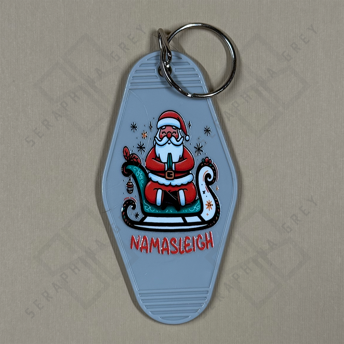 Keychain with Santa Claus design and 'Namasleigh' text on a beige background