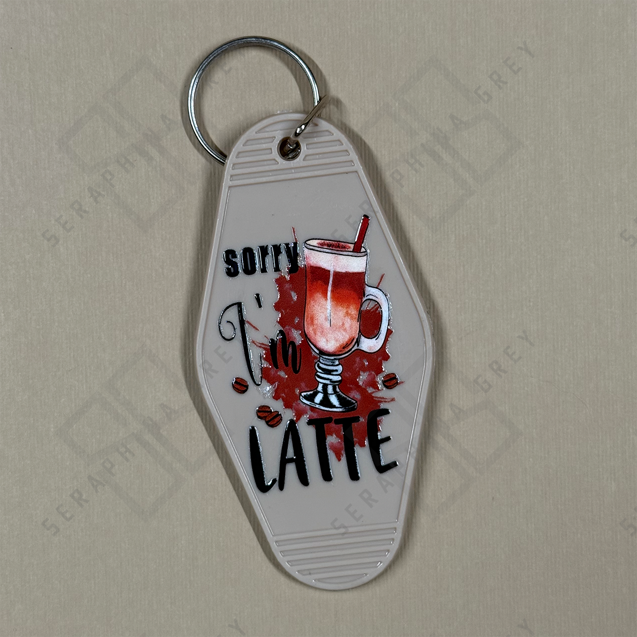 Keychain with a design of a coffee cup and text Sorry I'm Latte on a beige background