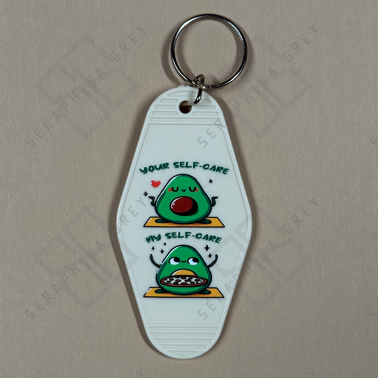 Keychain with avocado design and text Your selfcare vs My selfcare. healthy avocado or pizza avocado, on a beige background