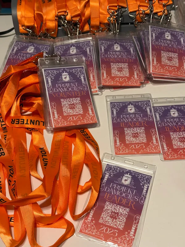 A batch of printed event badges attached to orange lanyards